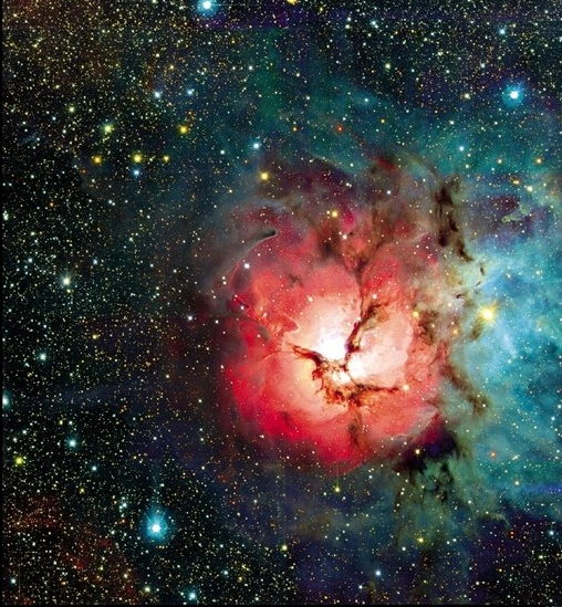 Birthplace of the Stars, 3. The Trifid Nebula in Sagittarius is about 4,500 light-years away near the center of the galaxy. Its pinkish color is due to the presence of hydrogen which has been ionized by a group of young stars in the center of the nebula. This expanding area is surrounded by bands of dust and globules of cold gas, which will condense to form new stars. © CFH Telescope